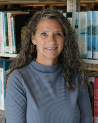 Heather Blankenship Professional headshot of Heather Blankenship smiling and looking directly at the camera. She is wearing business attire and is photographed in front of a bookshelf filled with books