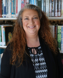 Melissa Smith Professional headshot of Melissa Smith smiling and looking directly at the camera. She is wearing business attire and is photographed in front of a bookshelf filled with books